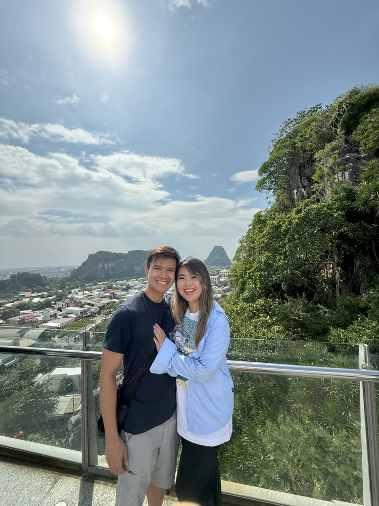 Edward and his wife at a lookout with mountains behind them